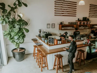 RE/MAX Çankaya ticari gayrimenkul ve dükkan değerleme formu. Çalışanların ve müşterilerin bulunduğu, faal durumdaki modern kafe işletmesi iç mekanı.